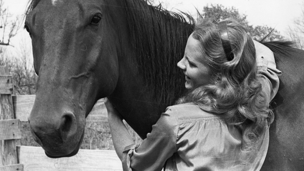 Reba with arms around horse